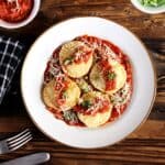 Quick and simple ravioli in roasted garlic pasta sauce served in a white plate.