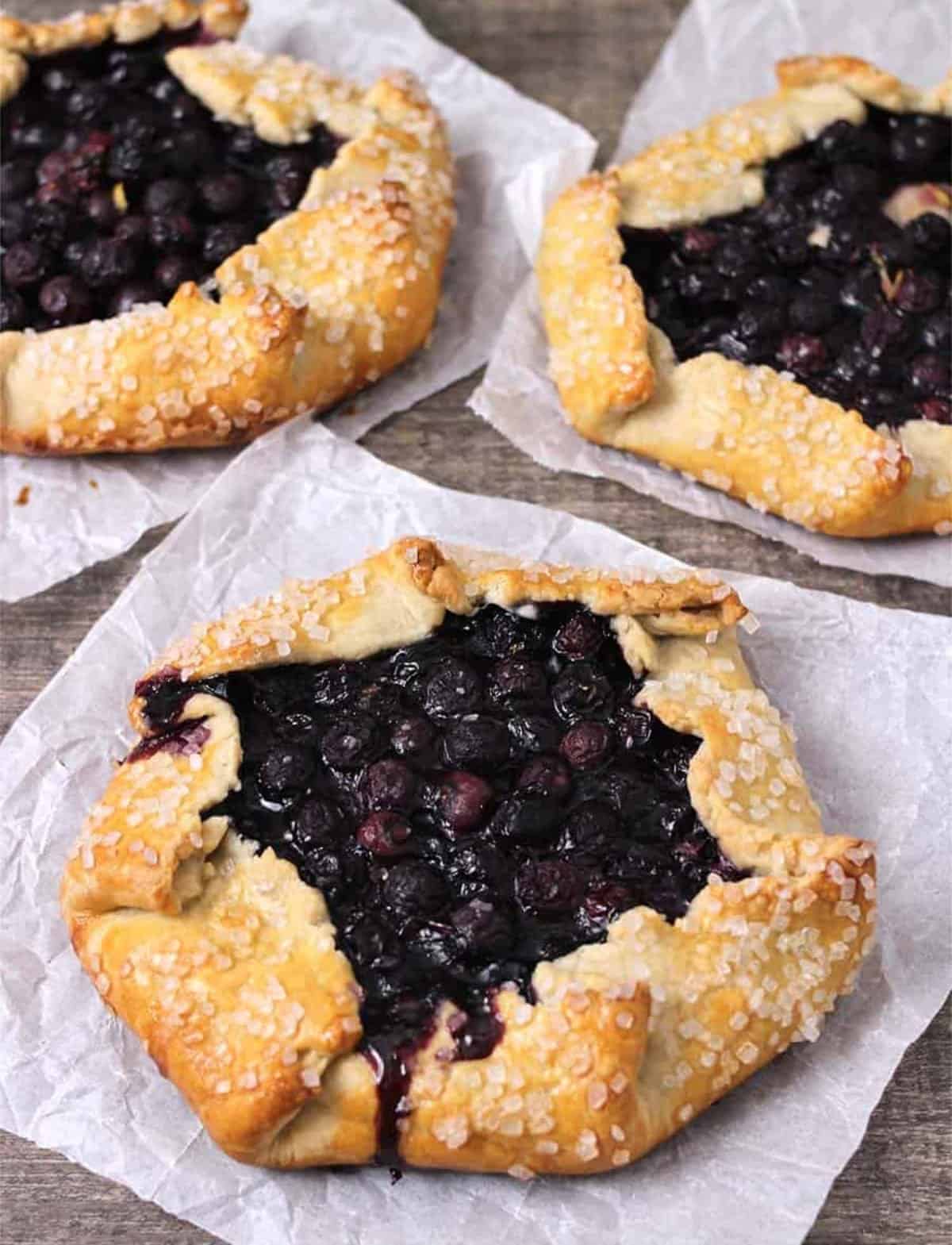 Best Mini blueberry crostatas or galettes on white parchment paper.