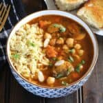 Simple Pasta Soup with Tomato Sauce base served in ceramic bowl along with toasted bread rolls on the side.