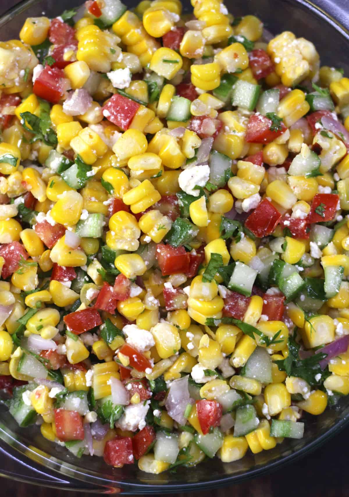 Easy corn salad recipe with cucumbers, onion, tomato, feta and lemon olive dressing.