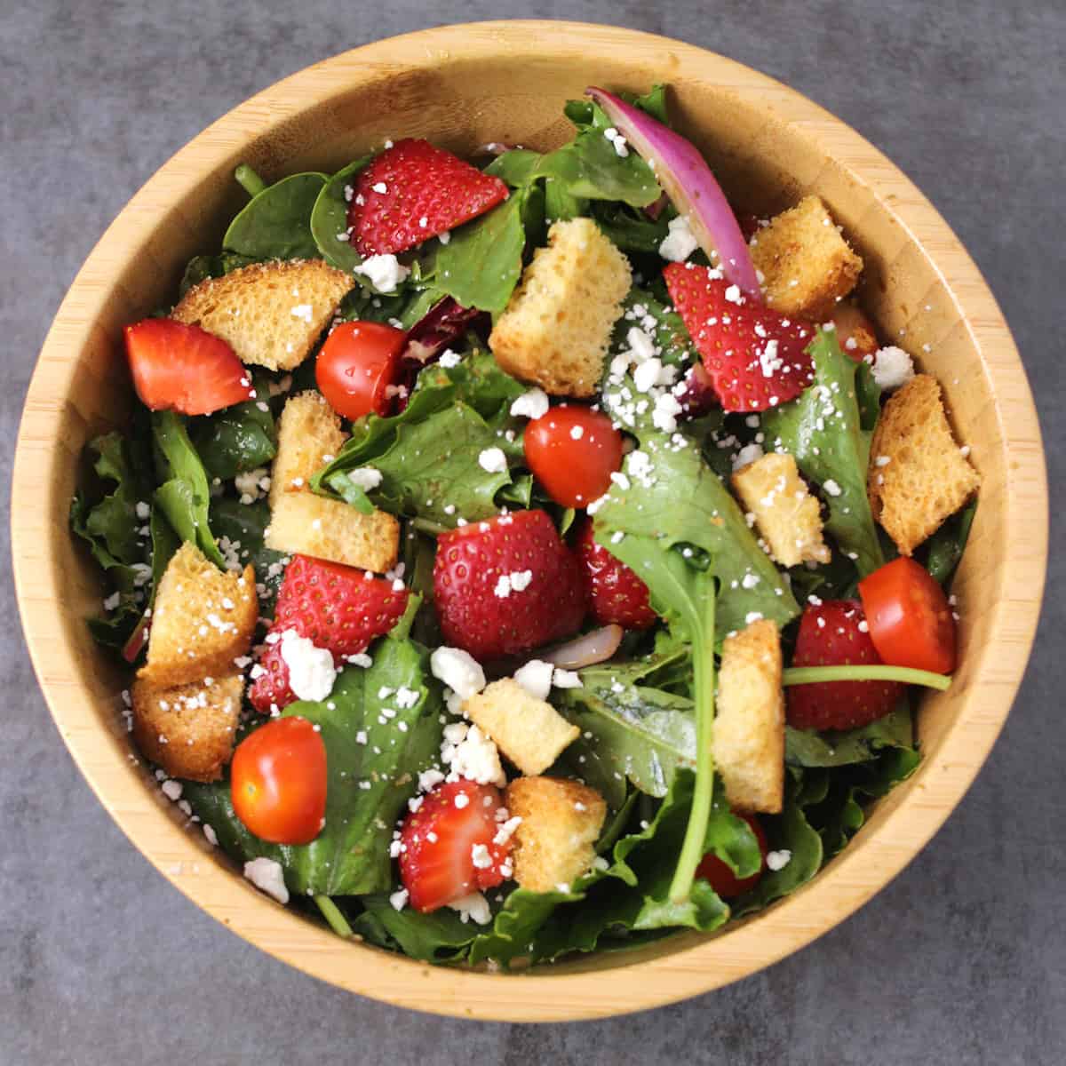 Strawberry Salad with mixed greens, feta cheese, onions, tomatoes, and balsamic vinaigrette dressing.